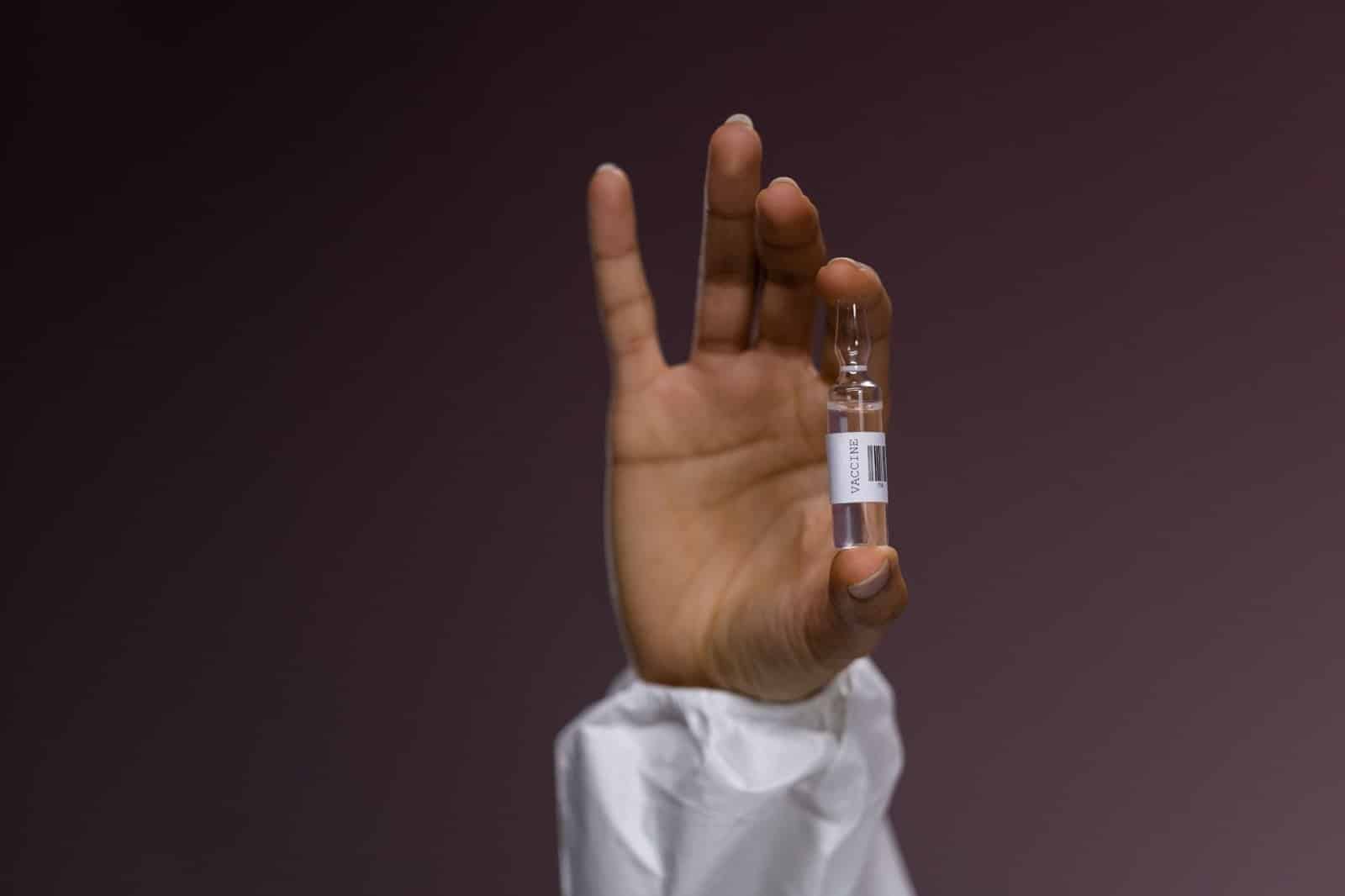 Mão segurando um frasco de composto de vacina