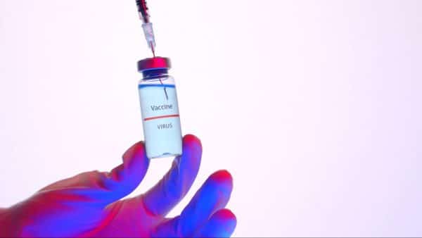 Frasco com composto da vacina do covid sendo adicionado a seringa 